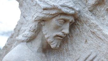 Steinskulptur von Jesus, der das Kreuz trägt